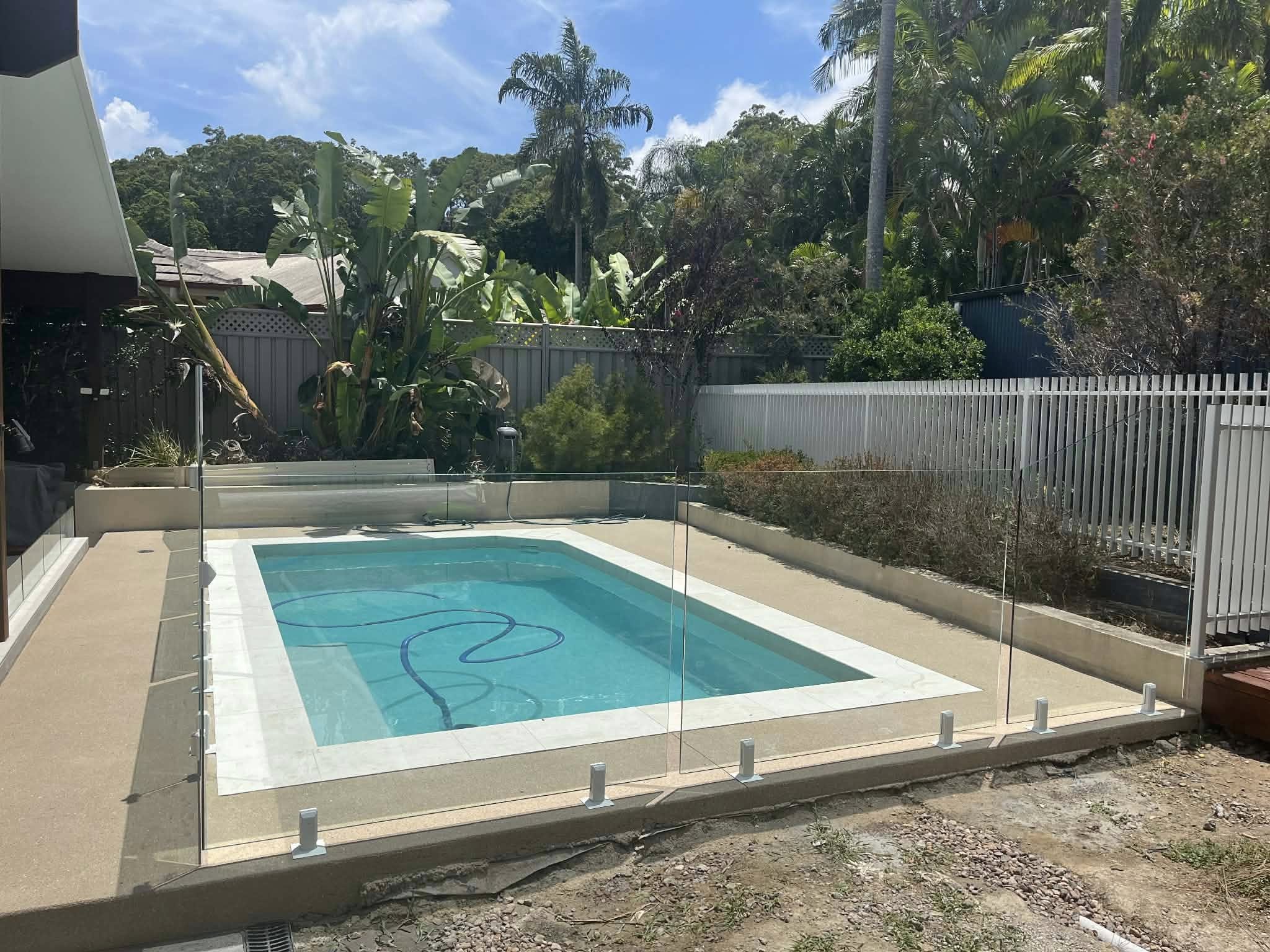Frameless glass pool fence with silver spigots on a new build